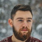 Man with a beard and short hair, wearing a patterned sweater, looking thoughtfully against a snowy background, representing a consultant in B2B and B2C growth strategies.